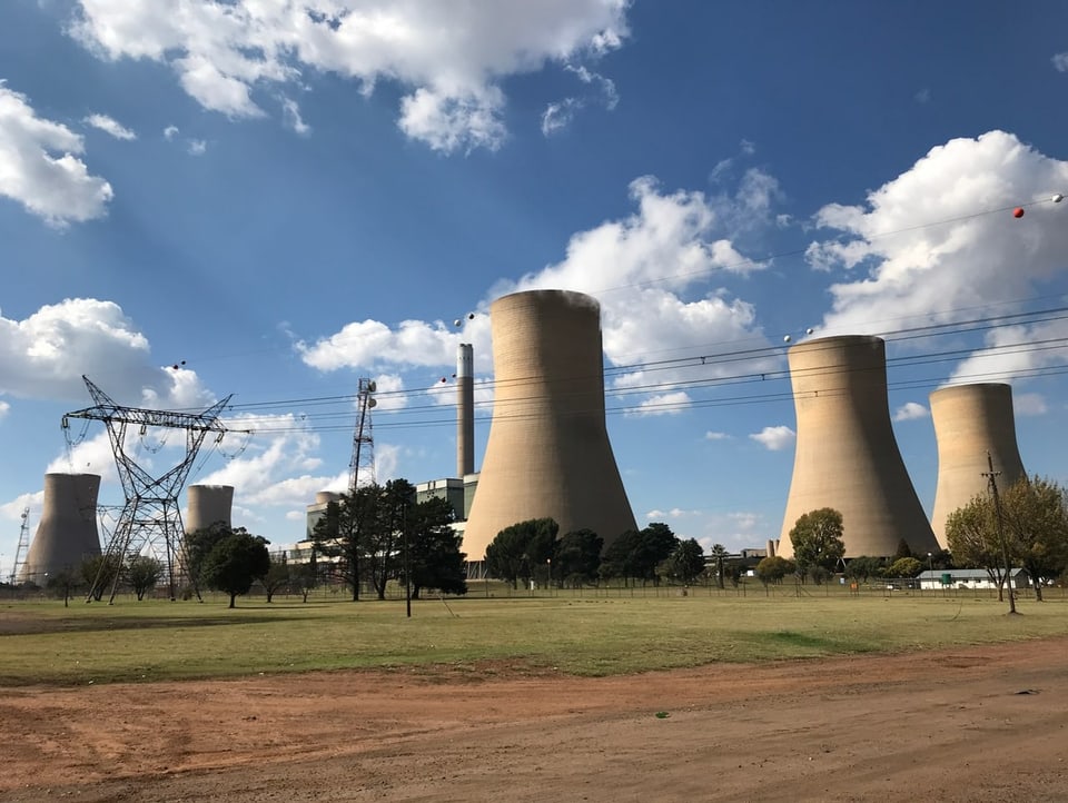 Blick auf ein Kohlekraftwerk in Südafrika. Es stehen mehrere Kühltürme nebeneinadner.