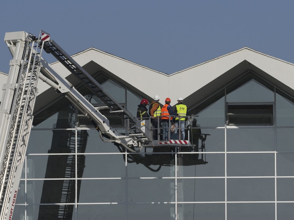 Arbeiter auf Hubarbeitsbühne an Gebäude.