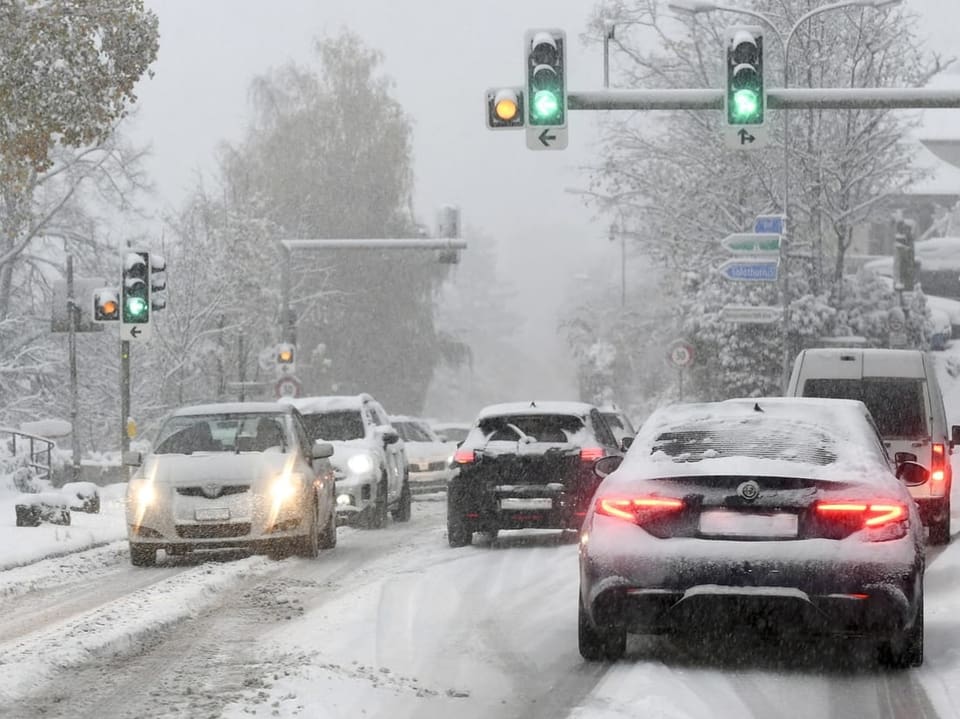 Autos fahren durch Schnee bei Grünlichtern.