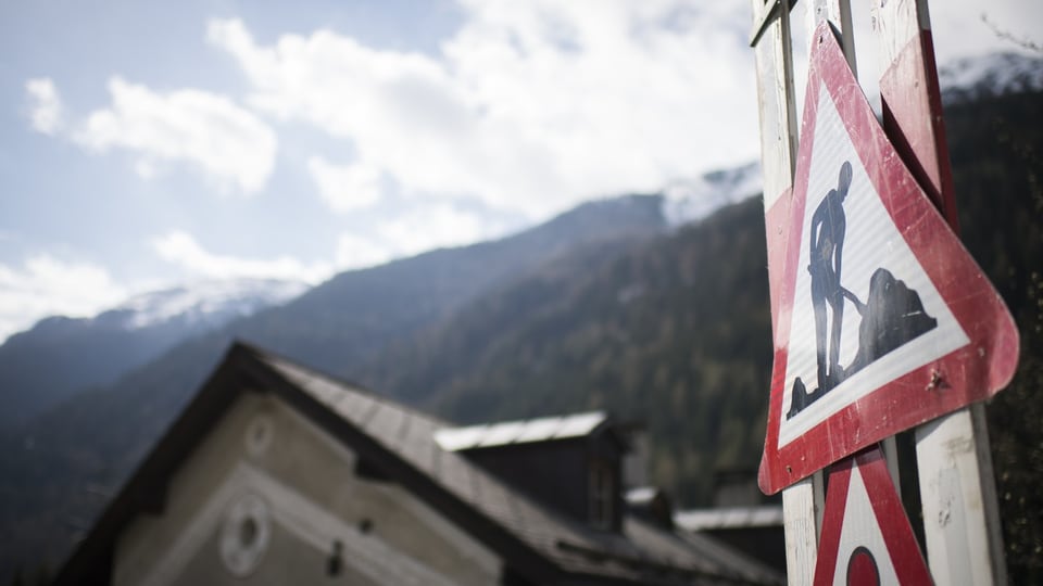 schild vor blauem himmel hügel und hausdach