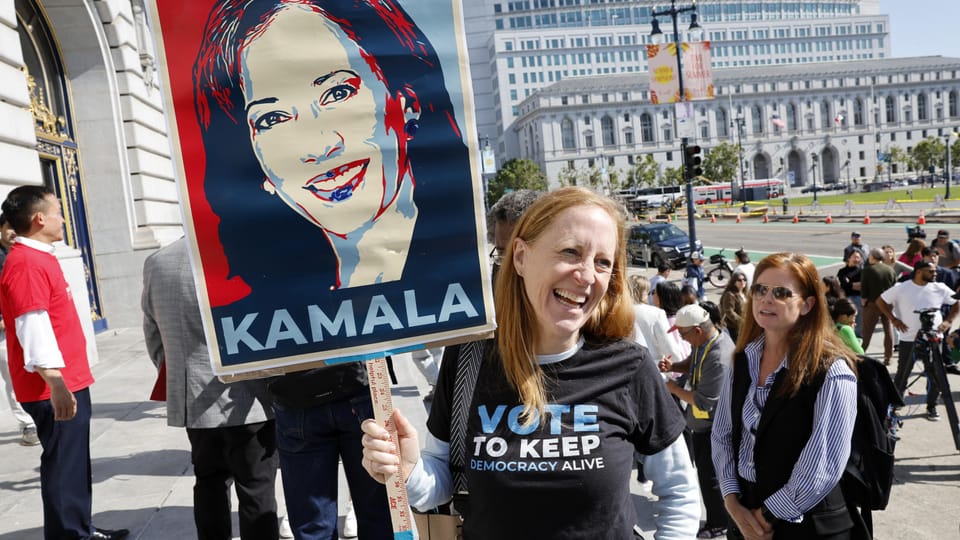 Frau hält Kamala-Plakat bei politischer Veranstaltung.
