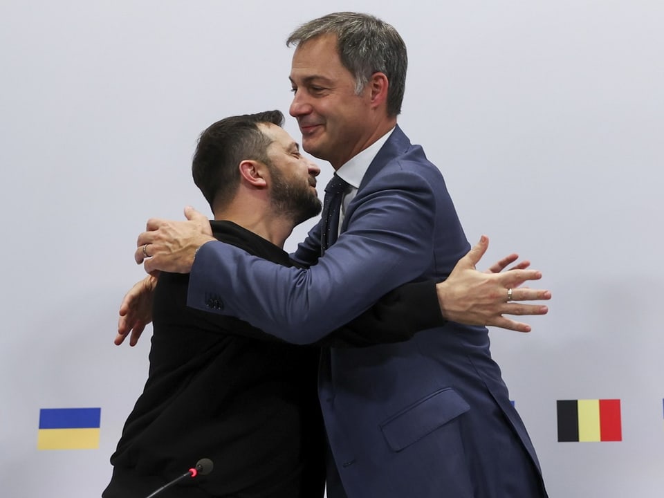 Der ukrainische Präsident und der belgische Premierminister umarmen sich.