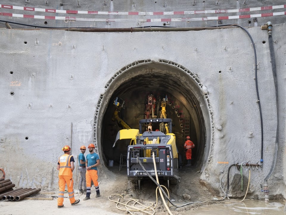 Arbeiter vor Tunnelbohrmaschine am Tunneleingang.