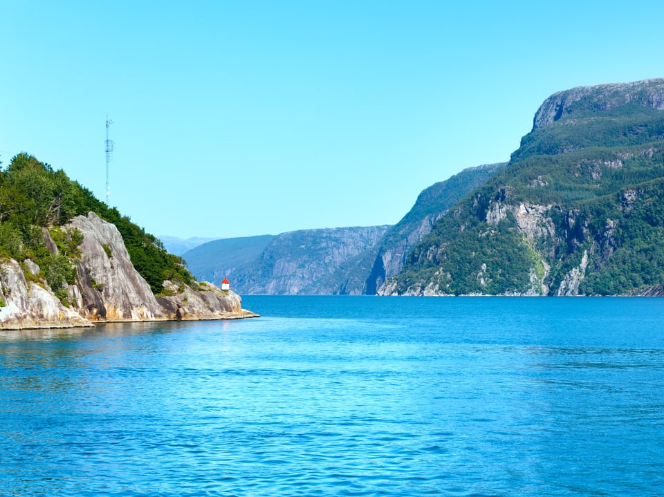 Fjordlandschaft mit klarem blauem Wasser und felsigen Bergen.