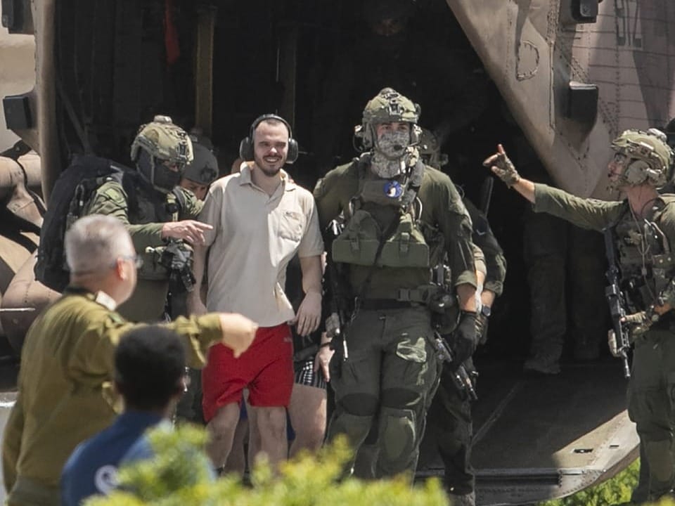 Person in roter Shorts und heller Bluse mit Soldaten und Helikopter.