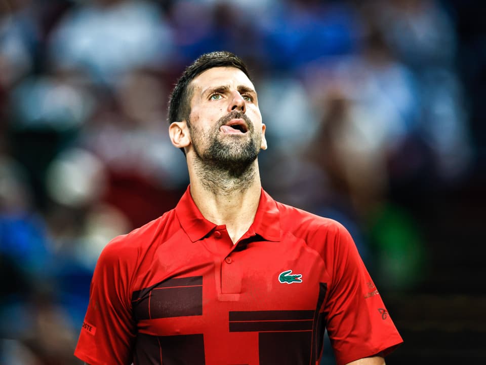 Tennisspieler im roten Shirt auf dem Platz.