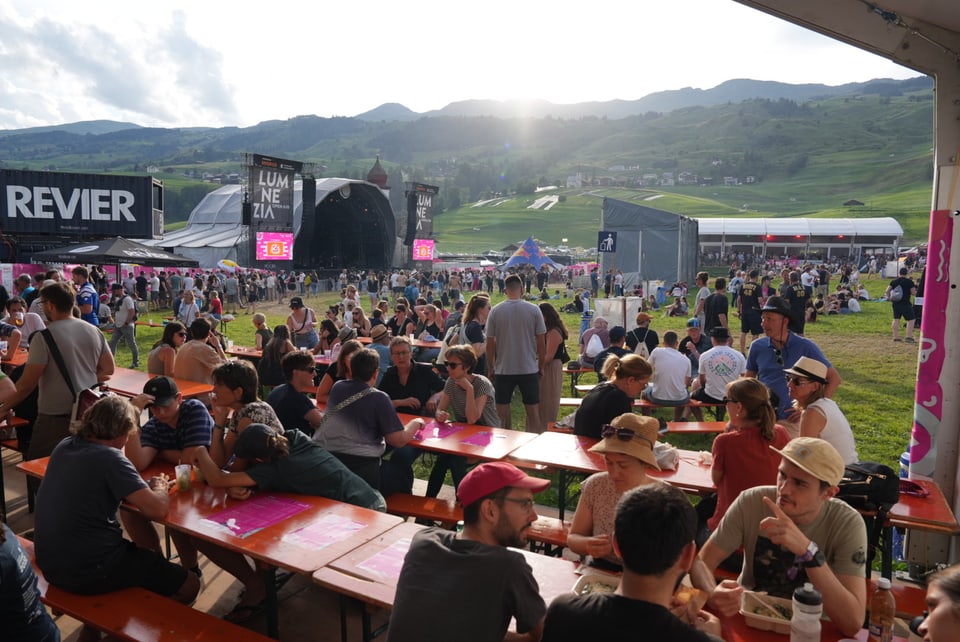 Menschenmenge bei einem Musikfestival auf einem grünen Feld am Open Air Lumnezia 2024.