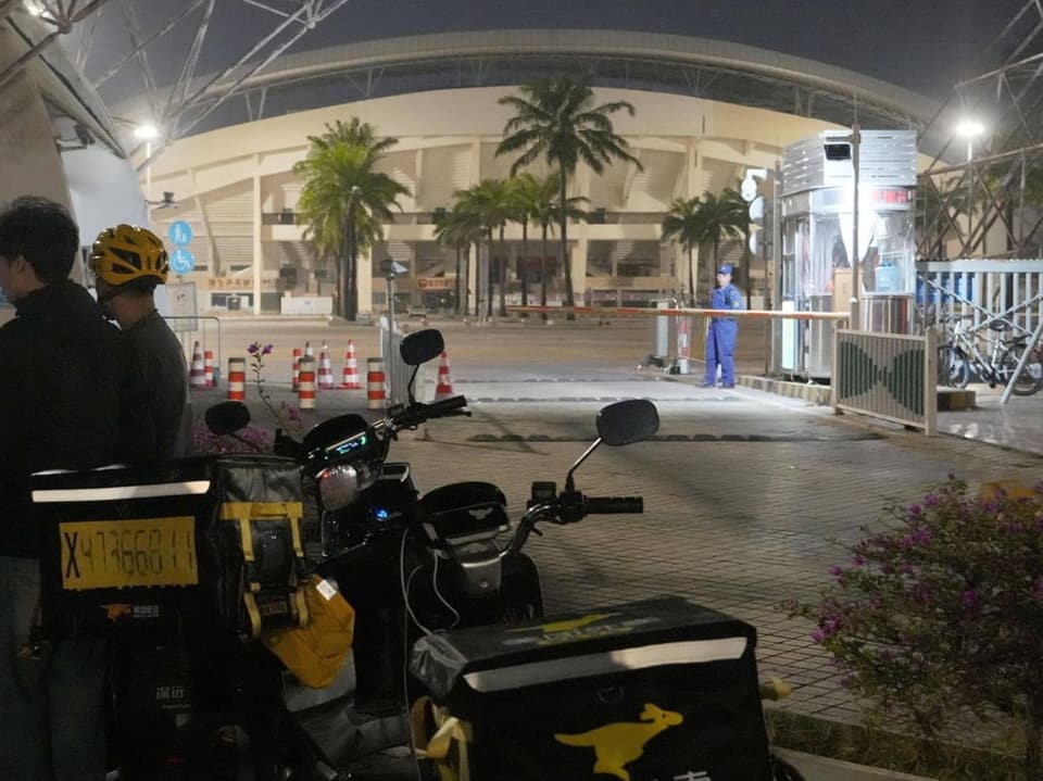 Motorräder und Menschen vor einem Gebäude bei Nacht.