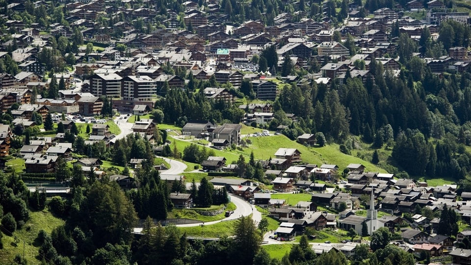 Luftaufnahme von Verbier mit grossen Appartmentgebäuden und der Kirche.