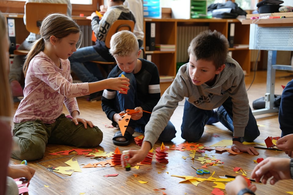 Kinder basteln auf dem Boden in Klassenzimmer.