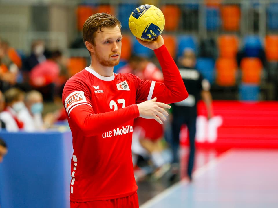 Handballspieler im roten Trikot bei Spielvorbereitung.