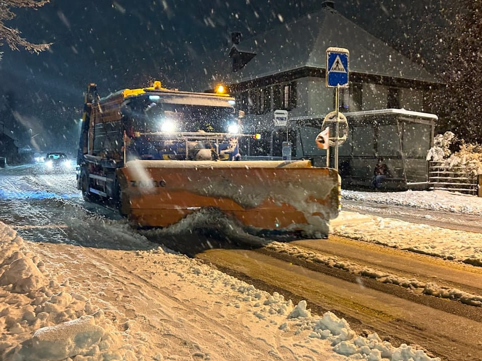 Schneepflug räumt nachts eine Strasse.