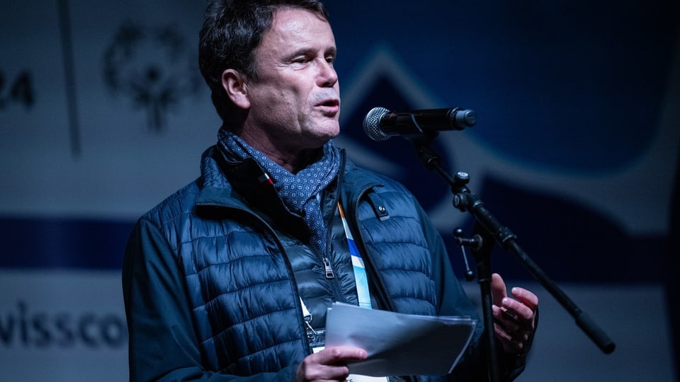 Mann mittleren Alters hält eine Rede am Mikrofon bei einer Veranstaltung.