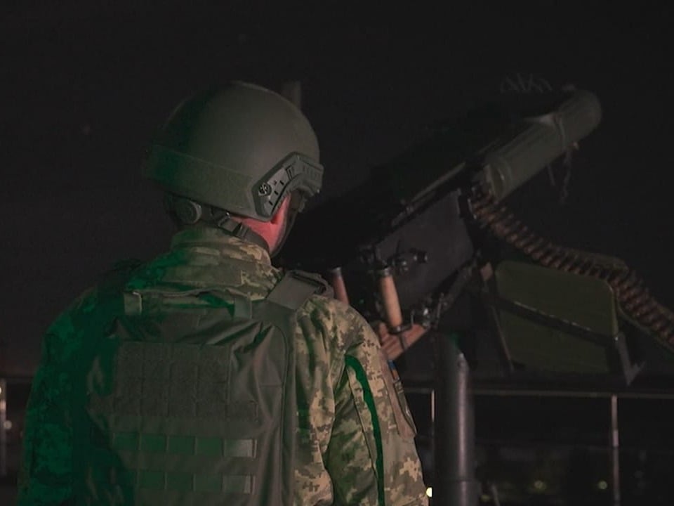 Soldat mit Helm bei Nacht neben Geschütz.