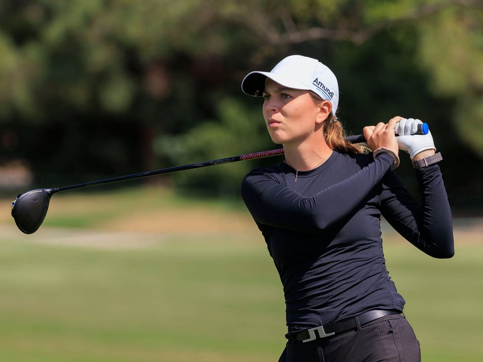 Frau schwingt Golfschläger auf dem Golfplatz.