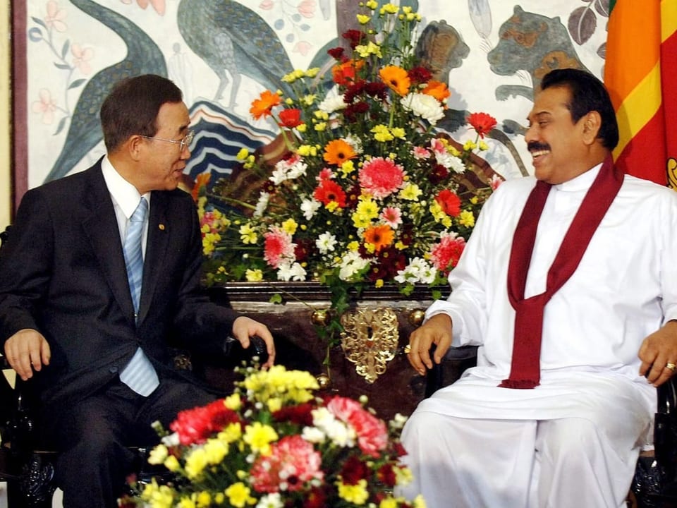 Ki-Moon und Staatspräsident Mahinda Rajapaksa sitzen sich gegenüber und lächeln sich zu