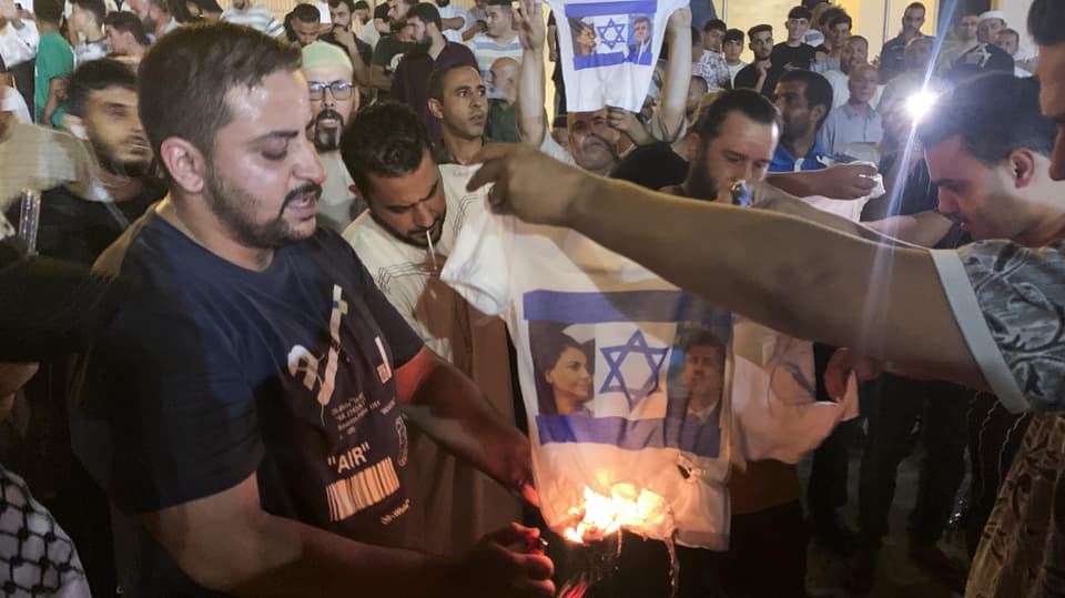 Meschen verbrennen T-Shirts mit der Flagge Israels und den Gesichtern der beiden Aussenminister