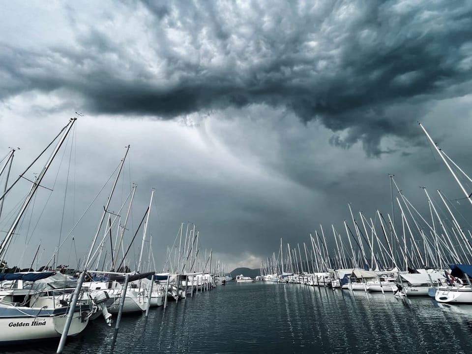 Stürmischer Himmel über einem Yachthafen mit Segelbooten.