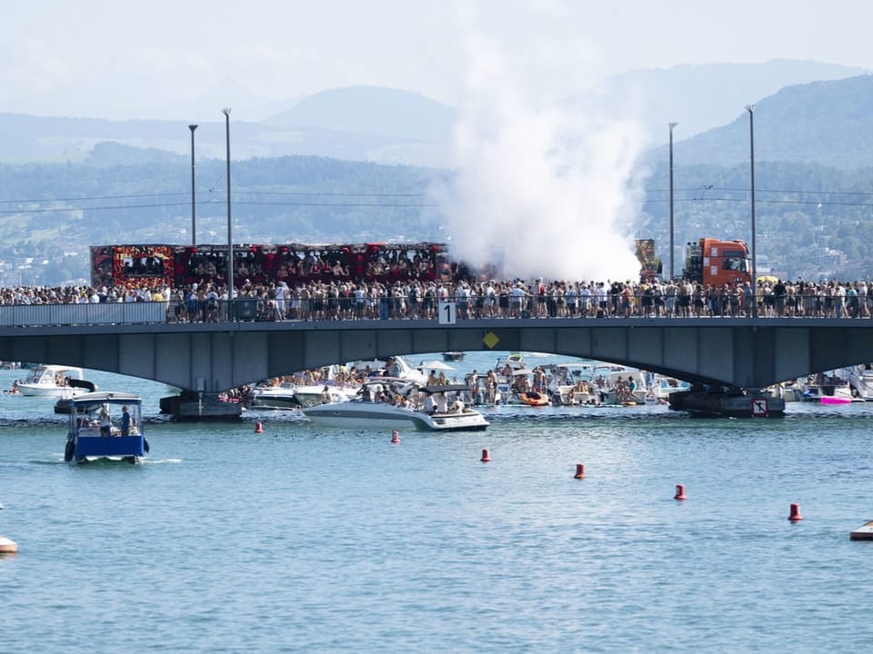 Menschenmenge auf Brücke über See mit Booten.