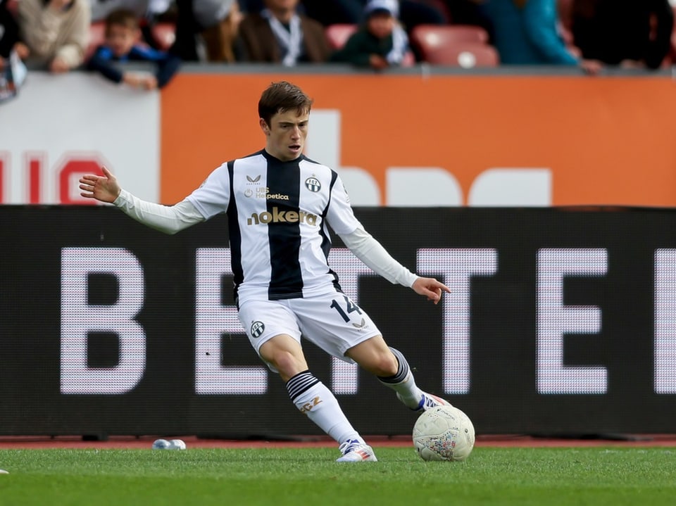 Fussballspieler mit schwarz-weissem Trikot tritt den Ball.