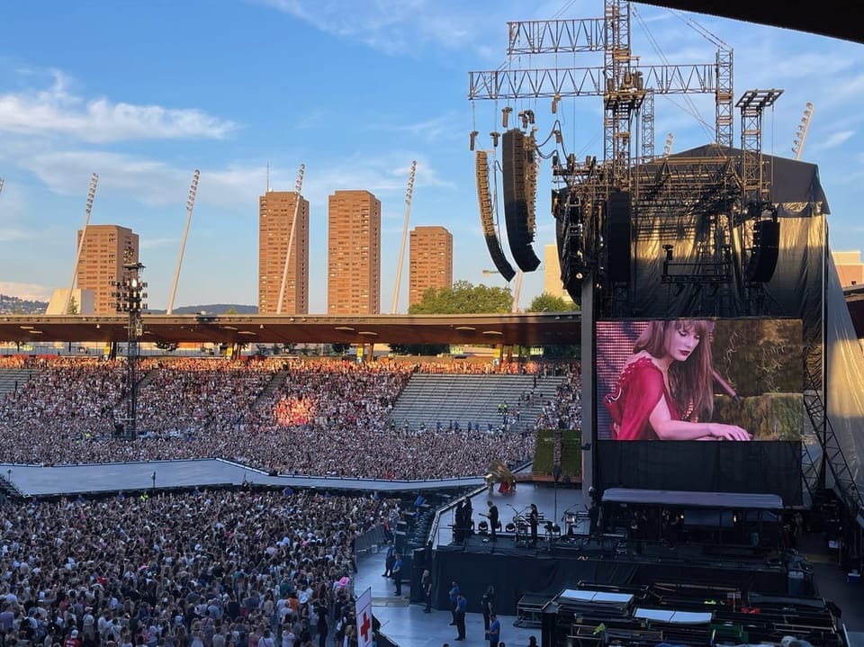 Grosses Konzert in einem Stadion mit Menschenmenge und Videobildschirm.