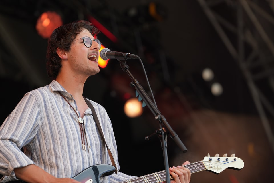 Musiker singt und spielt E-Gitarre auf der Bühne.