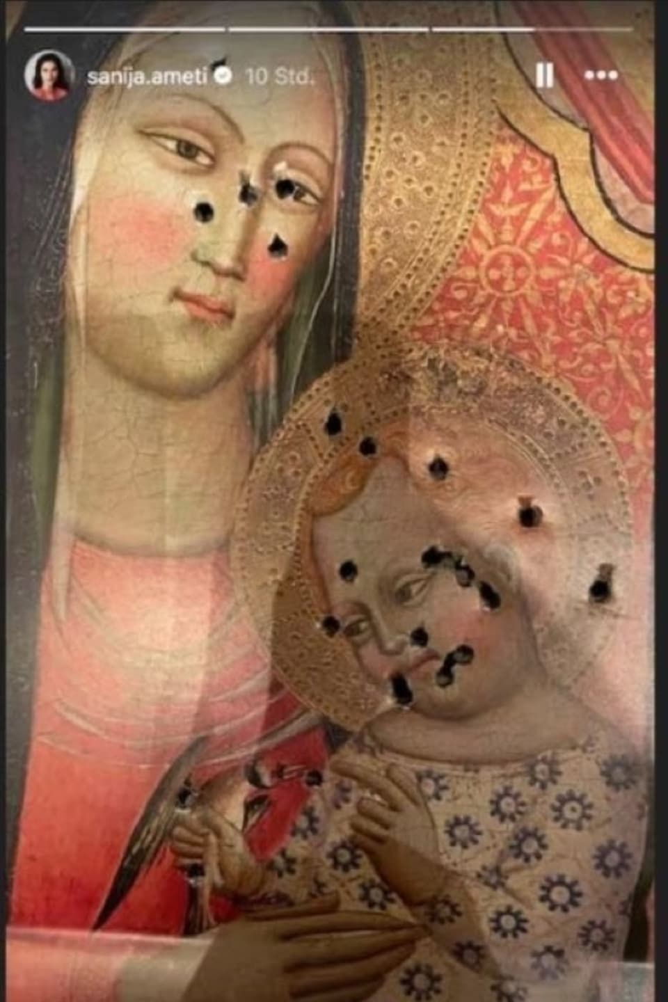 Old painting of a saint with bullet holes.