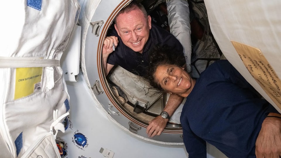 Zwei Astronauten lächeln in einer Raumstation.