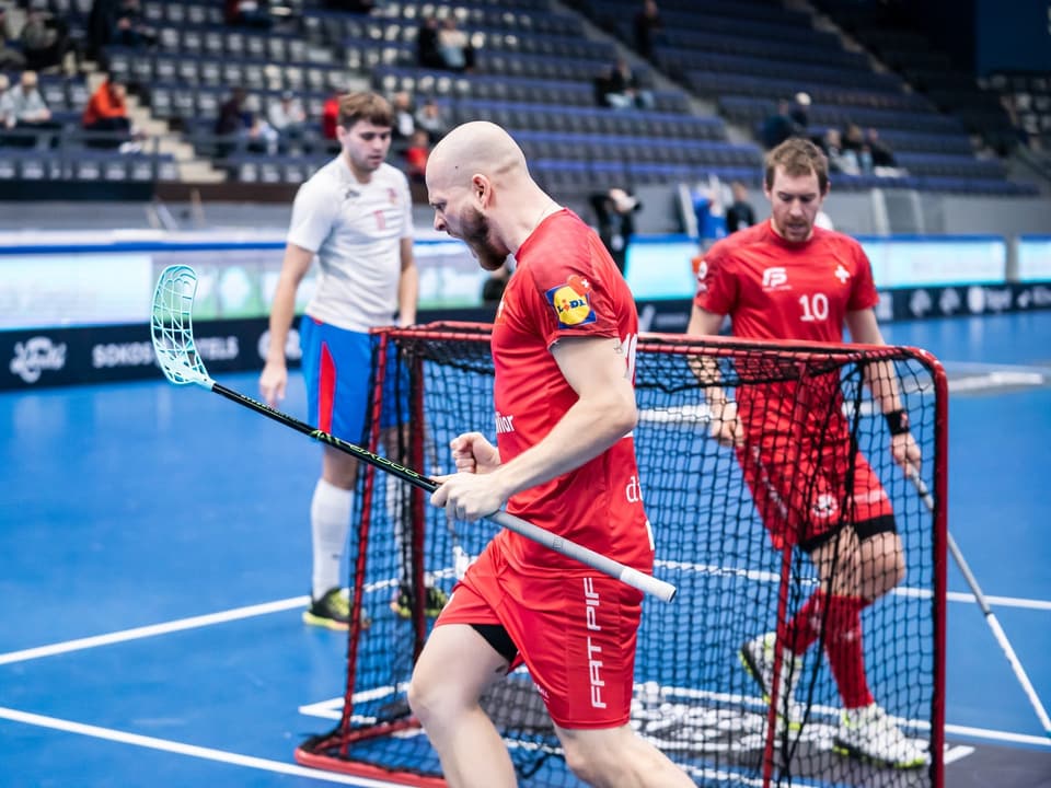 Mann im roten Trikot jubelt auf dem Unihockeyfeld.