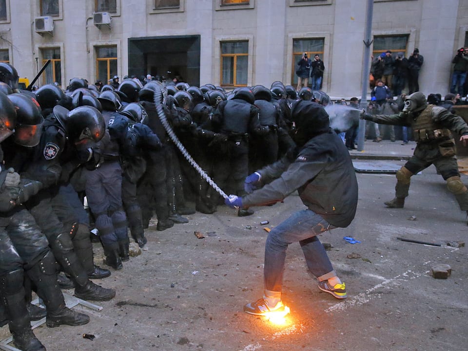 Demonstrant greift Polizisten mit Kette an.