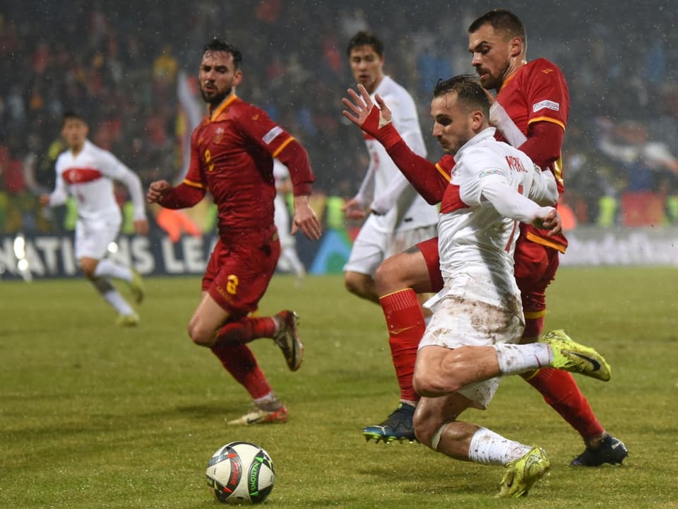 Fussballspieler kämpfen um den Ball im Regen.