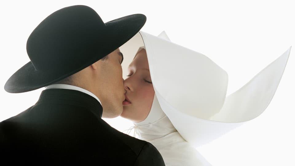 Ein Mann in Priestergewand und eine Frau in Nonnenkleidung küssen sich.
