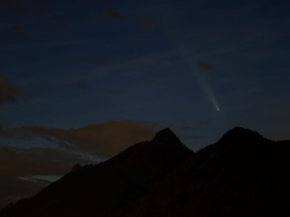 Nachtansicht von Bergen mit Komet am Himmel.