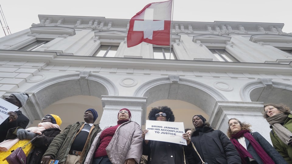 Personengruppe vor weissem Gebäude mit schweizer Flagge.