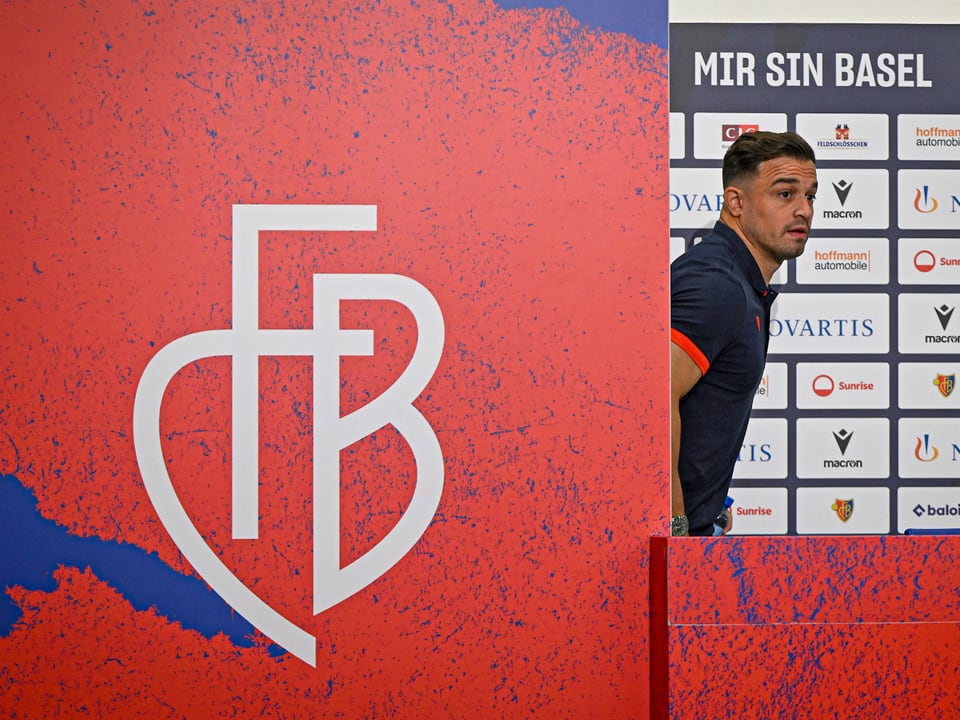 Fussballspieler vor einer Wand mit Sponsorenlogos und FCB-Logo.