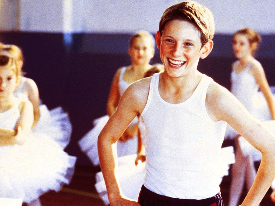 Ein kleiner Junge steht inmitten von jungen Ballerinas