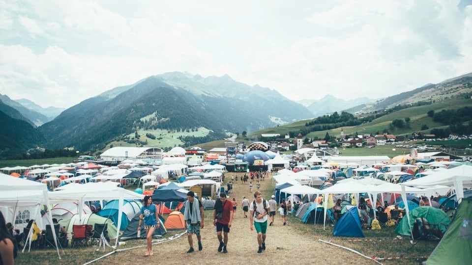 Das Openair Lumnezia in vollem Gang: Zelte und Festivalbesucherinnen vor der schönen Bergkulisse.