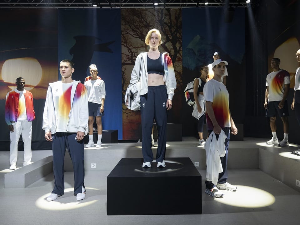 Modenschau mit Models in sportlicher Kleidung auf einer beleuchteten Bühne.