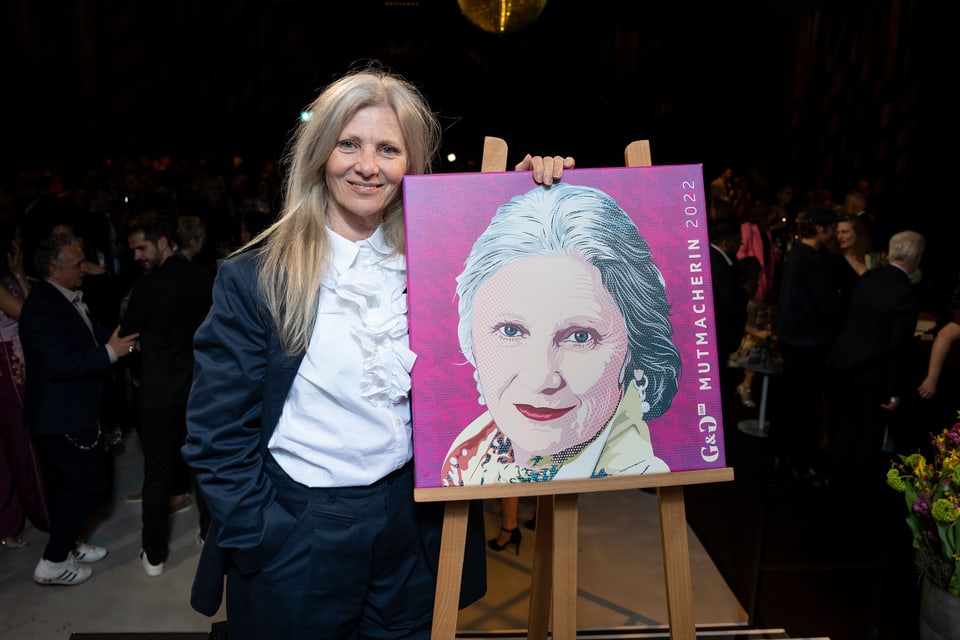 Ältere Frau neben einem Porträt ihres Gesichts