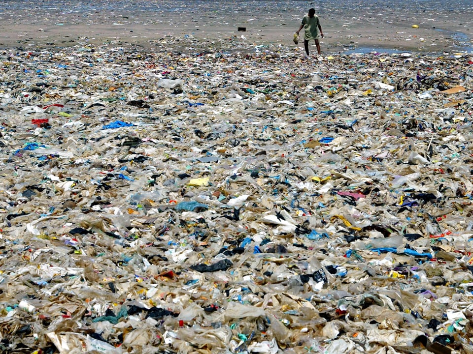 Die Bucht von Mumbai mit Plastikmüll und einem Mann im Hintergrund