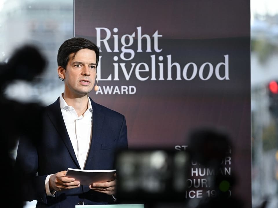 Mann hält Rede vor dem Right Livelihood Award Banner.