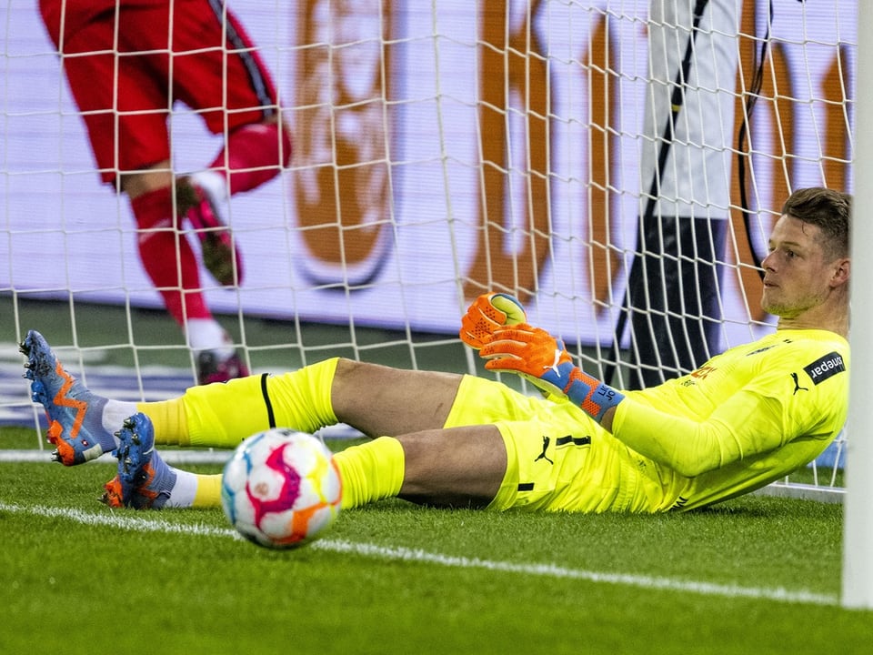 Torwart in gelbem Trikot hält Fussball im Netz.