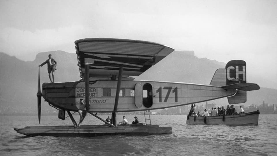 Wasserflugzeug mit Menschen in einem Beiboot