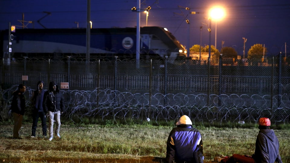 Migrangen vor dem eingezäunten Bahngelände.