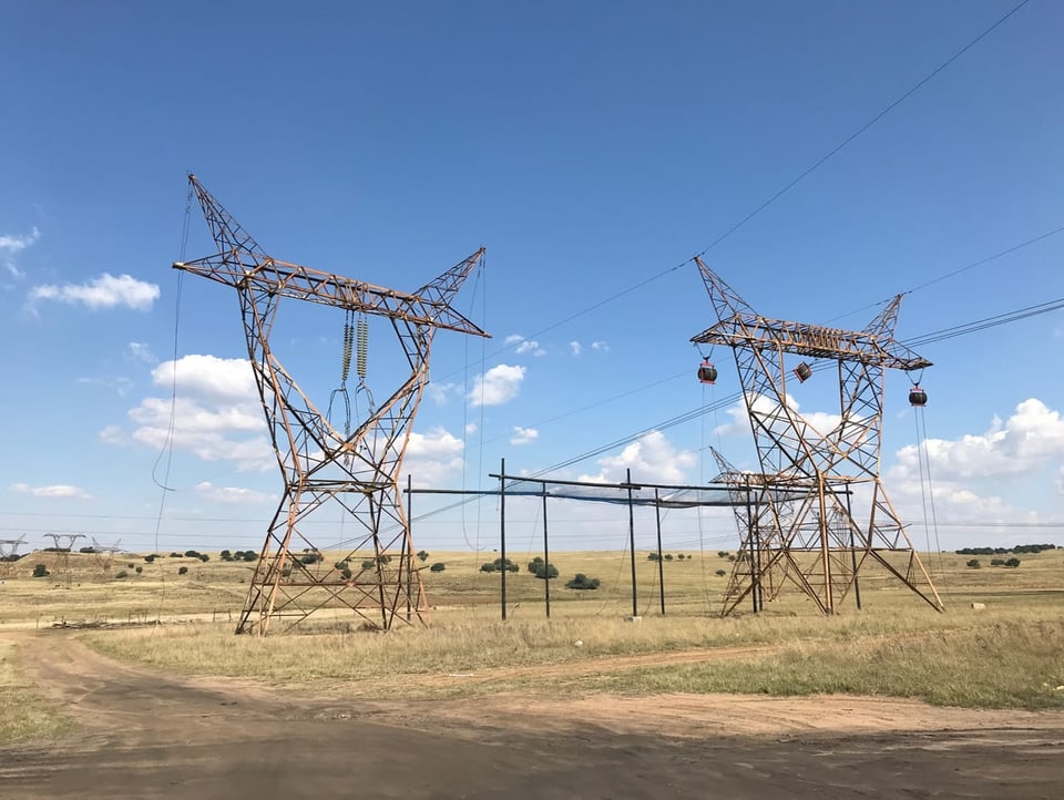 Strommasten in ein karg bewachsenen Gegend in Südafrika.