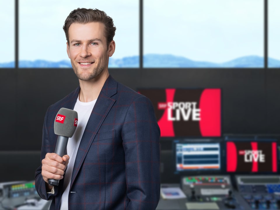 Mann mit Mikrofon im Fernsehstudio mit Monitoren.