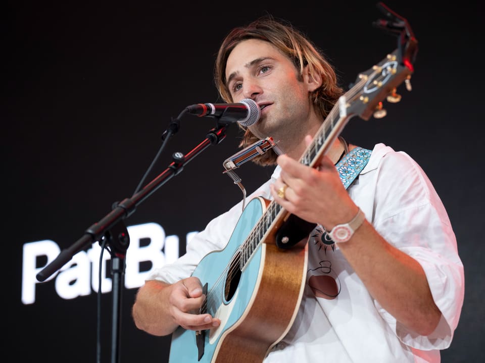 Mann spielt Gitarre auf der Bühne.