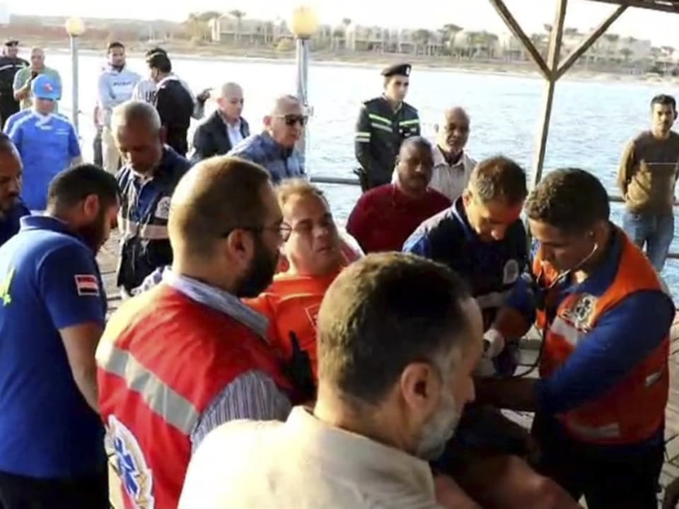 Ersthelfer kümmern sich um verletzte Person auf einem Steg am Wasser.