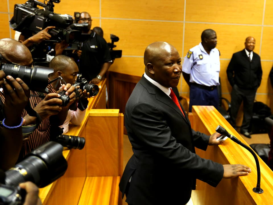Julius Malema vor Gericht, zahlreiche Kameras auf ihn gerichtet.