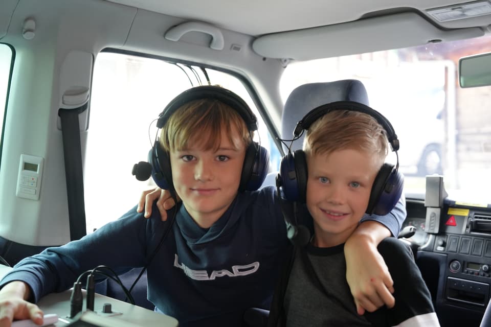 Zwei Jungen mit Headsets in einem Fahrzeug.